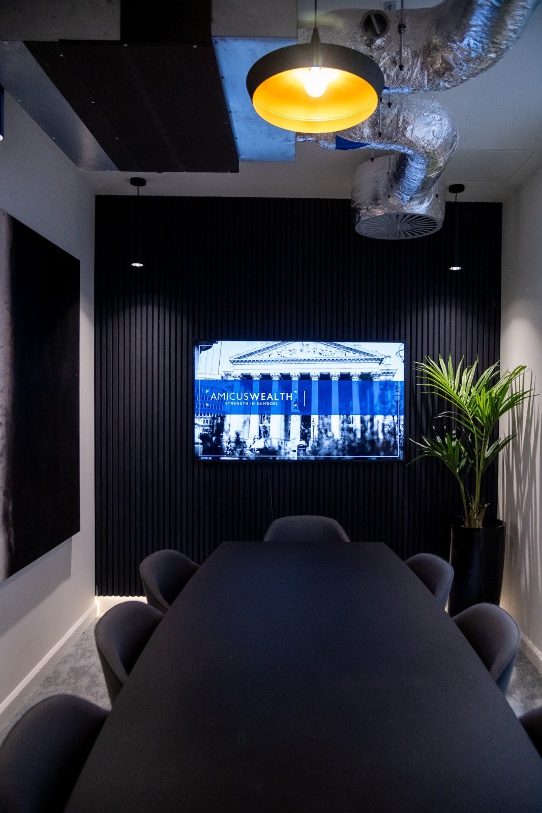 Data and AV cabling run to a wall-mounted display in a dark-panelled meeting room