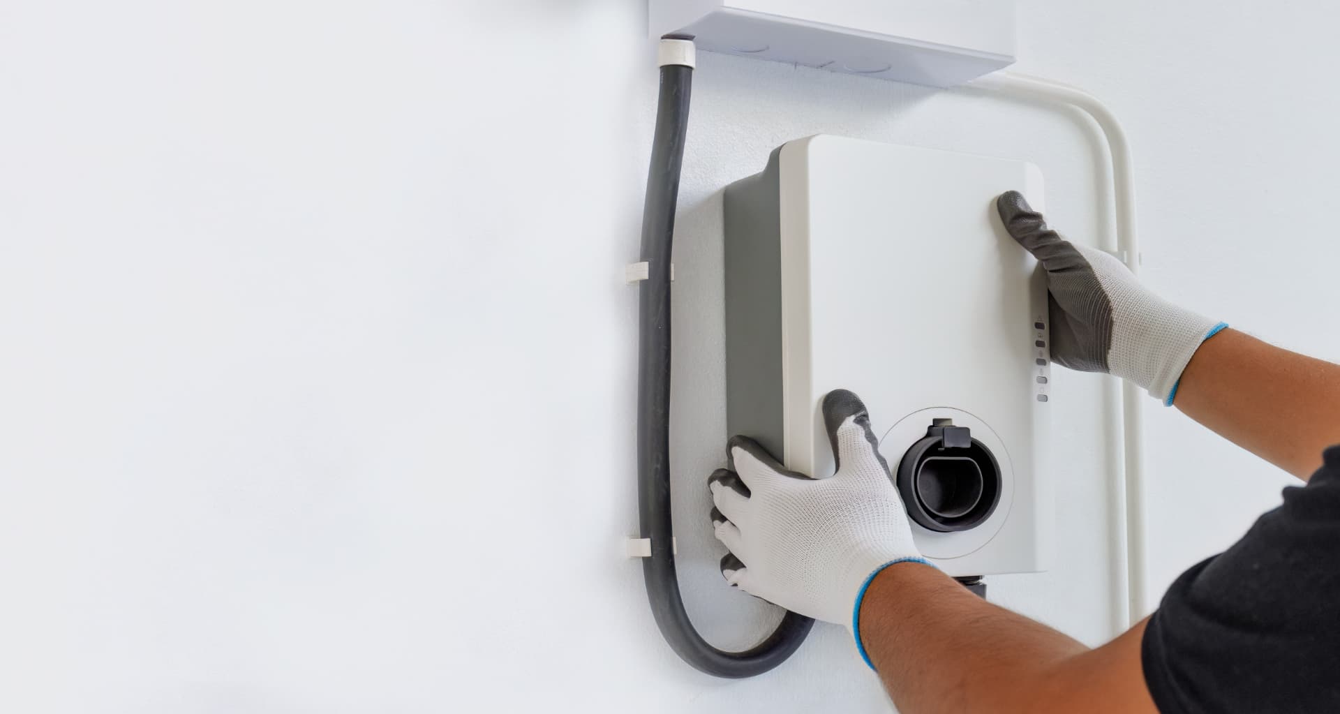 Electrician fitting a wall-mounted EV charge point and cable containment at a home in Loughton